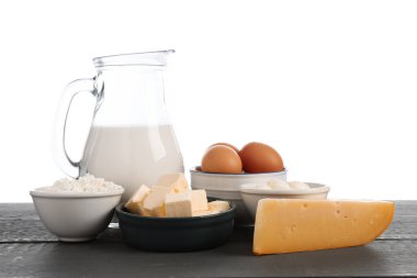 Gri ahşap masada beyaz arka planda farklı süt ürünleri ve yumurtalar