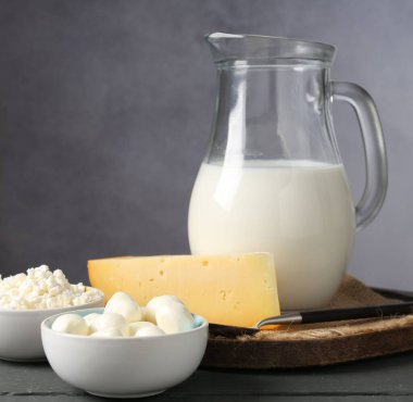 Gri ahşap masada farklı süt ürünleri, yakın plan.