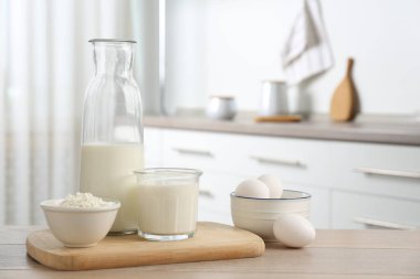 Mutfaktaki ahşap masada farklı süt ürünleri ve yumurtalar.