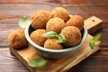 Tahta masadaki fesleğende fesleğen olan lezzetli kızarmış kroket topları, yakın plan.