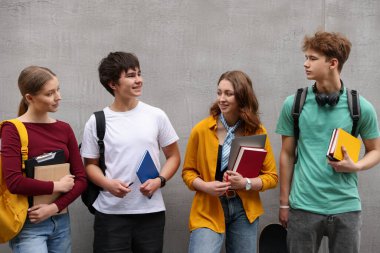 Gri duvarın yanında bir grup genç var.