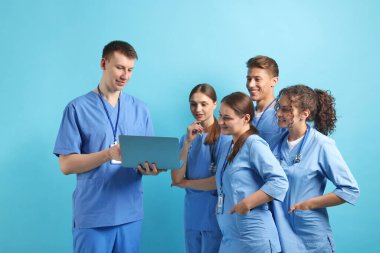 Açık mavi arka planda dizüstü bilgisayarı olan bir grup tıp öğrencisi.