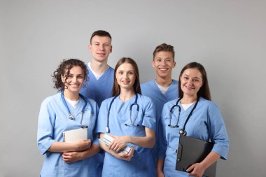 Açık gri arkaplan üzerine kitapları olan bir grup tıp öğrencisi