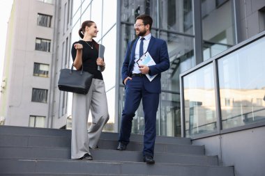 Mutlu iş arkadaşları ofis binasının yakınında bir şeyler tartışıyor.