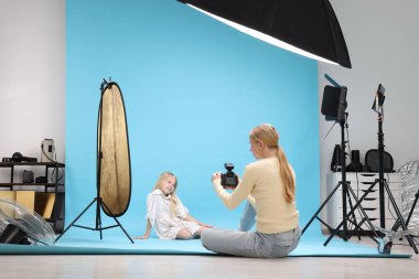 Profesyonel fotoğraf stüdyosunda modelle çalışan bir fotoğrafçı.