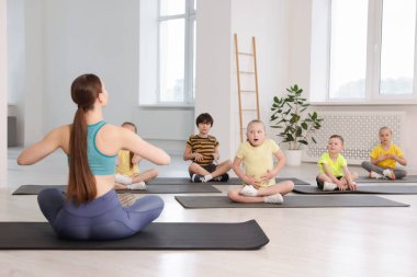 Sınıfta koçla yoga yapan bir grup çocuk.