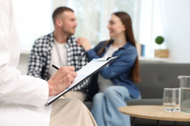 Tüp bebek (tüp bebek). Üreme kliniğinde doktorla görüşen çift, seçici odaklanma