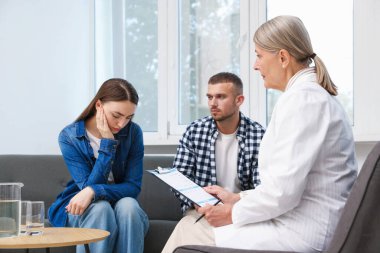 Tüp bebek (tüp bebek). Üreme kliniğinde doktorla görüşen üzgün çift.