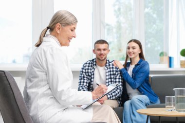 Tüp bebek (tüp bebek). Üreme kliniğinde doktorla görüşen çift, seçici odaklanma