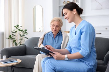 İçeride yaşlı bir kadını muayene eden bir hemşire. Ev sağlık hizmetleri