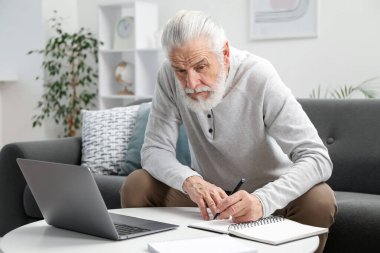 Üst düzey adam içeride online öğrenim görürken not alıyor. Kendi kendine çalışma.