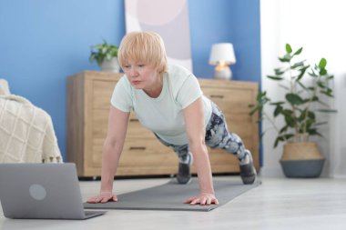 Spor giyim bölümünde son sınıf öğrencisi. Evde online ders sırasında kalas egzersizi yapıyor.