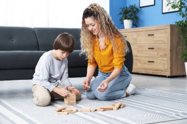Anne ve oğlu evlerinde yerde tahta bloklarla oynuyorlar.