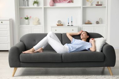 Uyum. Evdeki kanepede uzanmış gülümseyen kadın.