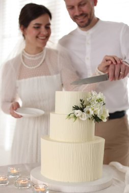 Evli çift evde bıçakla düğün pastası kesiyor, seçici bir odak noktası var.