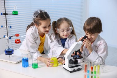 Çocuklar içeride masada kimyasal deneyler yapıyorlar.