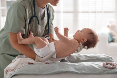 Klinikteki masada bebeği muayene eden çocuk doktoru, yakın plan.