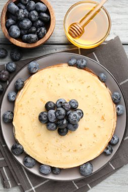 Gri ahşap masada yaban mersinli ve ballı leziz krepler.