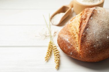 Bir somun taze ekmek, un ve çiviler beyaz ahşap masada, yakın plan. Metin için boşluk