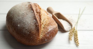 Taze ekmek, un ve çiviler beyaz ahşap masada, yakın plan.