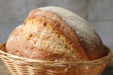 Hasır sepetin içinde bir somun taze ekmek masada, yakın plan.