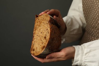 Gri arka planda taze ekmeği olan bir kadın, yakın plan. Metin için boşluk