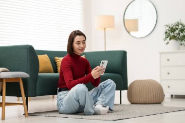 Evde modern akıllı telefon kullanan bir kadın.