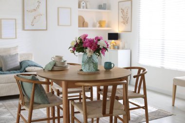 Odada güzel çiçekler ve bulaşık takımı olan yemek masası. İç tasarım