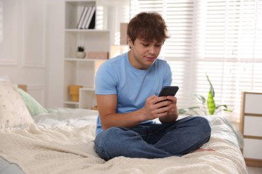 Ergen çocuk evde akıllı telefon kullanıyor.