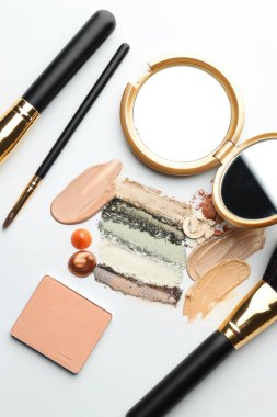 Farklı kozmetik ürünleri, makyaj fırçaları ve beyaz arka planda ayna, düz yatış