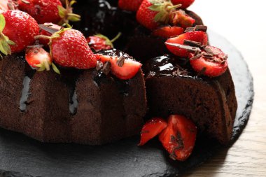 Çilekli lezzetli çikolatalı kek, ahşap masada, yakın plan.