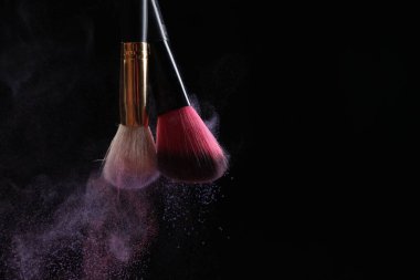 Siyah arka planda renkli göz gölgeli makyaj fırçaları, yakın plan. Metin için boşluk