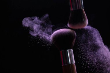 Siyah arka planda mor göz farlı makyaj fırçaları, yakın plan. Metin için boşluk