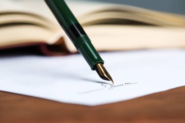 Kahverengi masadaki dolma kalemle noter belgesi imzalanırken, yakın plan