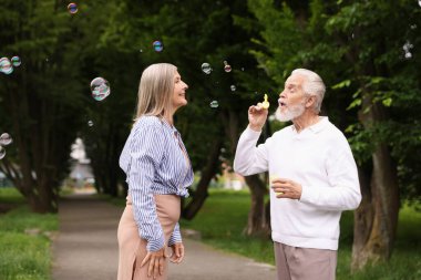 Güzel yaşlı çift parkta sabun köpüğüyle eğleniyor.