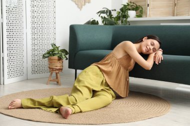 Uyum. Gülümseyen kadın evdeki kanepede uzanırken dinleniyor.