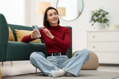 Evde modern akıllı telefon kullanan bir kadın.