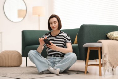 Evde modern akıllı telefon kullanan bir kadın.