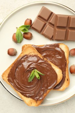 Lezzetli çikolatalı tostlar, parçalar, nane ve fındıklar ışık masasında.