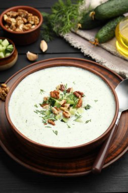 Siyah ahşap masada servis edilen dereotlu ve cevizli lezzetli salatalık çorbası.