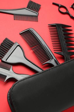 Farklı kuaför aletleri ve kırmızı arka planda çanta, yakın plan