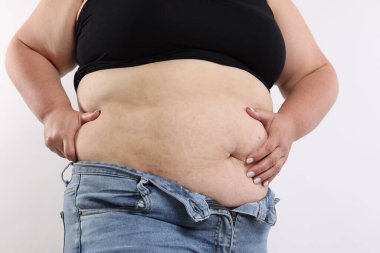 Beyaz arka planda aşırı göbek yağı olan kadın, yakın plan.