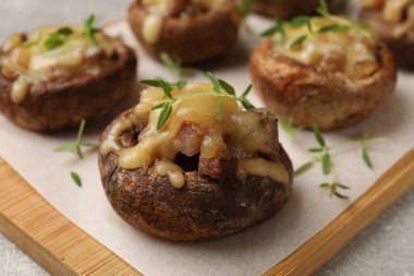 Eritilmiş peynirli lezzetli mantarlar ve gri masadaki kekik, yakın plan.