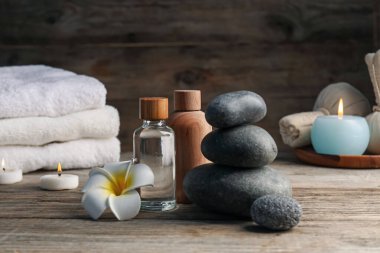 Kozmetik ürünleri ve spa taşlarıyla ahşap masaya yakın plan kompozisyon.