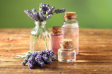 Ahşap masada lavanta şişeleri ve çiçekler, yakın plan.