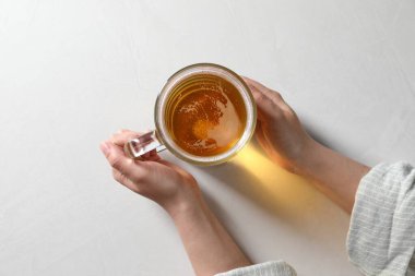 Beyaz masada cam bardakta birası olan bir kadın.