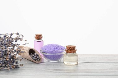 Doğal gaz, deniz tuzu ve lavanta çiçekleri ahşap masada beyaz arka planda.