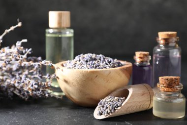 Siyah masa üzerinde doğal yağ ve lavanta çiçekleri, yakın plan.