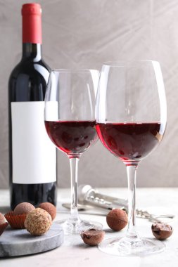 Kırmızı şarap ve yer mantarı şekerleri beyaz masada gri arka planda, yakın plan