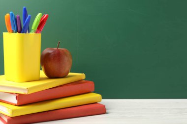 Farklı okul kırtasiyesi ve beyaz ahşap masada kırmızı elma karatahtaya karşı, yazı için yer